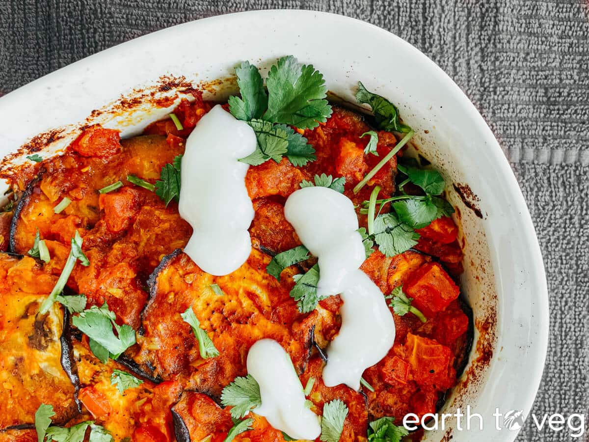 Casserole dish full of borani banjan with yogurt and cilantro.