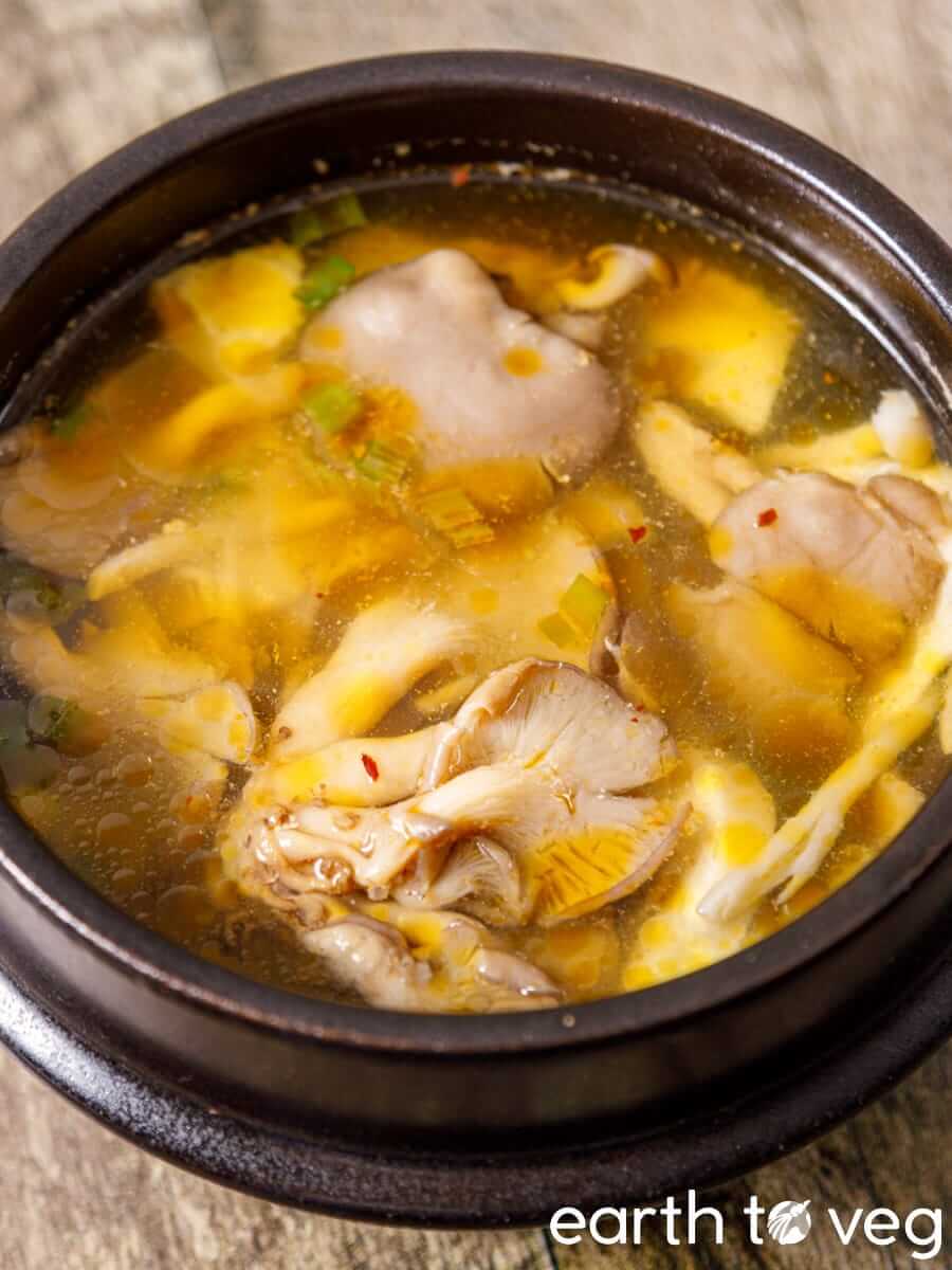 Oyster mushroom soup in a clay pot with tender oyster mushrooms, ginseng, and scallions.